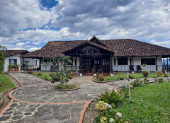 A wide shot of a white building with a red tile roof and a stone pathway in front.