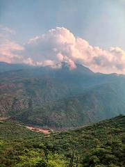 A mountainous landscape with lush greenery under a cloudy sky, featuring a building nestled in the valley.