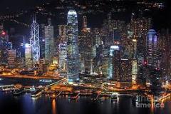 Here's a description of the image:This is a nighttime view of the illuminated Hong Kong skyline, showcasing numerous skyscrapers reflected in the water.