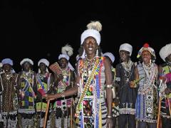 A group of men are dressed in traditional attire and standing in a row, posing for a photo.