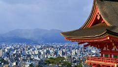 Une vue panoramique de Kyoto avec un bâtiment japonais traditionnel au premier plan et des montagnes en arrière-plan.