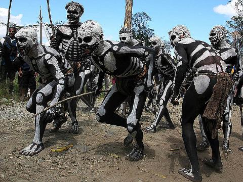 A group of men in Papua New Guinea are dressed in black and white skeleton body paint, likely for the Goroka Show Festival.
