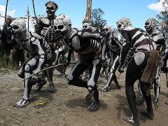A group of men in Papua New Guinea are dressed in black and white skeleton body paint, likely for the Goroka Show Festival.
