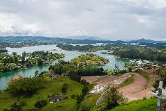 An expansive view of a lush, green landscape dotted with islands in a lake, under a cloudy sky.