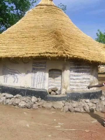 Bamako to Kangaba Historic Day Tour with Kamablon Visit A traditional thatched-roof hut in Mali features intricate blue and white patterns and animalistic art.