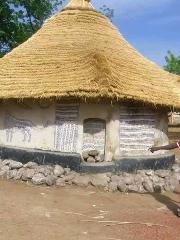 Bamako to Kangaba Historic Day Tour with Kamablon Visit A traditional thatched-roof hut in Mali features intricate blue and white patterns and animalistic art.