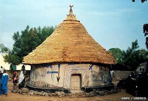 Bamako to Kangaba Historic Day Tour with Kamablon Visit A round, thatched-roof dwelling decorated with painted symbols and figures, is seen on a sunny day with people nearby.