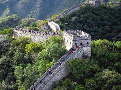 An aerial view of the Great Wall of China, teeming with tourists, winding through lush green hills.