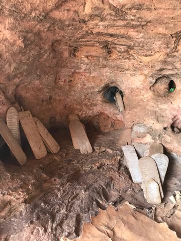 Wooden tablets with inscriptions are displayed in a cave or rock formation.