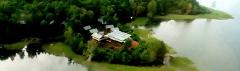 Lake Murray Lodge (Kiunga) Aerial view of Lake Murray Lodge surrounded by lush green trees, with a lake reflecting the sky, offering a serene and natural setting.