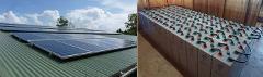 The image shows solar panels on a roof (left) and a bank of batteries (right), indicating a solar power system setup.