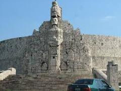Merida and Uxmal Airplane Tour Certainly! Here's a description of the image, fitting within your character limit:The image shows a large, intricately carved stone monument, likely Mayan in style, with a car parked in front.