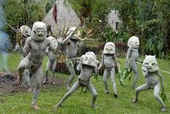 Goroka to Madang Walk Certainly! Here's a description of the image within the character limit:The image shows a group of performers in Papua New Guinea, covered in clay paint and wearing distinctive masks, likely during a cultural event in the Highlands region.