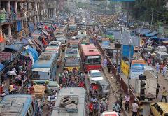 3-Day Dhaka Heritage & Culture Tour — Old Palaces, Lost Cities & Zamindari Mansions A congested street in Dhaka is filled with buses, cars, and motorcycles, with a busy marketplace and buildings lining the road.
