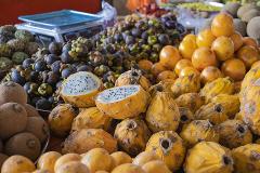 Cali City Tour This is a close-up shot of a colorful fruit stand, featuring a variety of tropical fruits like yellow dragon fruits, mangosteens, and sapodillas.
