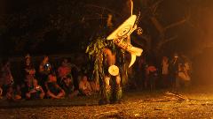 A Baining fire dancer wearing a traditional headdress and costume performs for a crowd at night in Papua New Guinea.