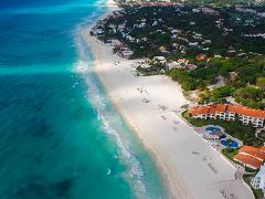 Riviera Maya Airplane Tours An aerial shot of the Riviera Maya shoreline features turquoise water, a pristine white sand beach, and lush green vegetation interspersed with beachfront properties and resorts.