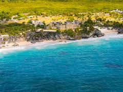 Riviera Maya Airplane Tours Aerial view of the Tulum archaeological site on the Riviera Maya, with ancient ruins perched on a cliff overlooking the turquoise Caribbean Sea.