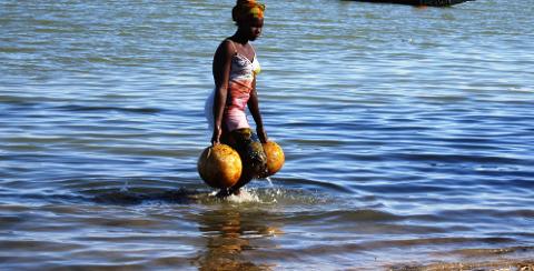 2 Day Ségou Cultural Tour from Bamako with Niger River Cruise A woman walks through water carrying large containers on her arms.