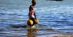 2 Day Ségou Cultural Tour from Bamako with Niger River Cruise A woman walks through water carrying large containers on her arms.
