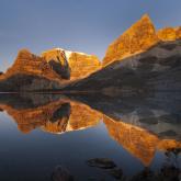 Sierra Nevada del Cocuy - 7 Day Trek Certainly! Here's a description of the image within the character limit:Majestic, golden mountains are reflected in a still, dark lake under a clear sky, creating a stunning mirrored landscape.