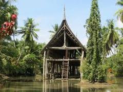 Certainly! Here's a description of the image within the specified character limit:A traditional stilt house with a steeply pitched roof stands in a river, surrounded by lush tropical vegetation.