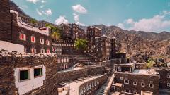 A picturesque view of Rijal Almaa village, Saudi Arabia, showcasing its unique stone architecture with colorful windows against a mountainous backdrop.