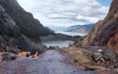 A scenic view of a lake surrounded by rocky mountains under a cloudy sky.