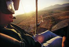 Playa Del Carmen Ultralight Aircraft Tour A pilot wearing a helmet is seen from inside an ultralight aircraft, with a scenic view of the landscape during a Playa Del Carmen tour.