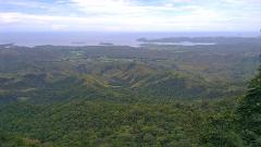 A scenic vista overlooking lush green mountains and valleys stretching toward the ocean and islands, possibly taken from the Sogeri Plateau near Port Moresby.