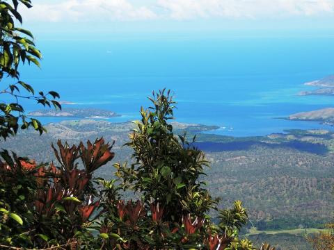 A scenic view from the Sogeri Plateau near Port Moresby, with lush greenery in the foreground and a stunning turquoise sea dotted with islands in the distance.