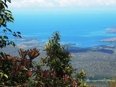 A scenic view from the Sogeri Plateau near Port Moresby, with lush greenery in the foreground and a stunning turquoise sea dotted with islands in the distance.