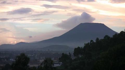 A picturesque view of Mount Nyiragongo with soft clouds overhead, overlooking Goma, Congo, captured at dusk or dawn.