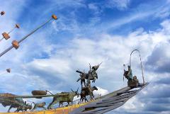 PANACHI – Chicamocha National Park A bronze statue of a historical scene featuring people on horseback and animals pulling carts, set against a backdrop of a bright blue sky with white clouds.