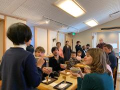 A group of people participate in a matcha making experience, with some holding bowls of matcha and others observing the process.