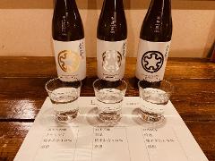 Three bottles of sake with three glasses of sake on a tasting sheet. The sake is from Kamikawa Taisetsu and includes Kitashizuku, Suisei, and GINPU.