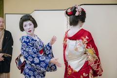 Geisha Ozashiki at Asakusa, a Quality Time Filled with Art and Japanese Culture Two geishas in traditional kimono perform for an audience, one in a blue floral pattern and the other in a red outfit adorned with flowers.