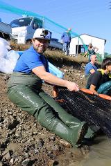 Professional breeder-guided Koi farm tour in the sanctuary of Nishikigoi A man in waders and a GoPro on his hat smiles while holding a net in a Koi farm tour.