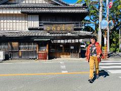 A woman walks across a street in front of a traditional Japanese building.