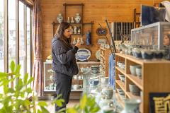 Ceramică și porțelan: Povești ale artizanilor din spatele meșteșugului A potter works at a wheel in a rustic studio, his hands shaping clay as he is illuminated by a modern desk lamp.
