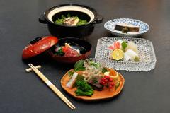 Daimyo Diary – Stroll with an Expert Guide at "Kenroku-tei" & Experience Traditional Tea Ceremony (With Breakfast) A Japanese meal is beautifully presented with various dishes, including sashimi, a stew, and intricately arranged small bites, accompanied by chopsticks.