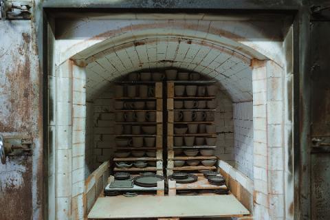 Pottery & Porcelain: Stories of the Artisans Behind the Craft An interior view of a kiln filled with rows of unglazed pottery cups and bowls, ready for firing.