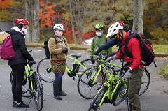 Embrace Beautiful Mother Nature on an E-Bike Tour of Yatsugatake Four people in athletic wear and helmets stand with their electric bikes surrounded by autumn foliage.