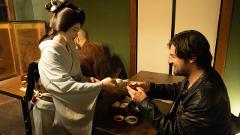 A geisha pours sake for a man during a traditional Japanese cultural experience.