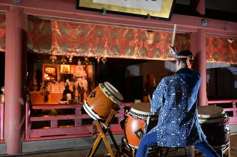 Nagano Half-Day Osuwa Daiko Spiritual Tour with Shrine Visit A performer in a blue patterned robe plays a large drum at a Japanese temple during a spiritual performance.