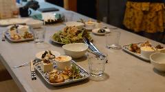 A spread of delicious Japanese cuisine, including salad, tofu, and baked dishes, is artfully arranged on a table setting with plates, bowls, glasses, and utensils.