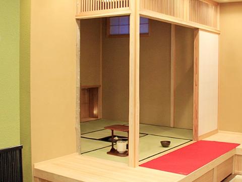 A minimalist Japanese tea room with tatami mats, a low table, and a red mat is set up for a casual matcha experience.