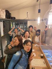 Six women are posing together in a bar, making peace signs and smiling for the camera.