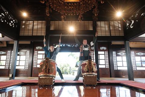 Nagano 2-Day Osuwa Daiko Tour with Shrine Rituals & Drum Lessons Two men play large taiko drums in a traditional Japanese room.