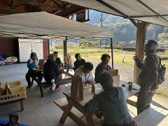 Explore the Local Morning Charm of Shiobara Onsen with a Satoyama Mini-Trek and Local Breakfast Delight A group of people are enjoying a casual outdoor breakfast under a tent at Shiobara Onsen, surrounded by scenic autumn foliage.